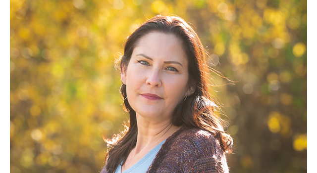 First Nations woman standing in a forest in the fall.